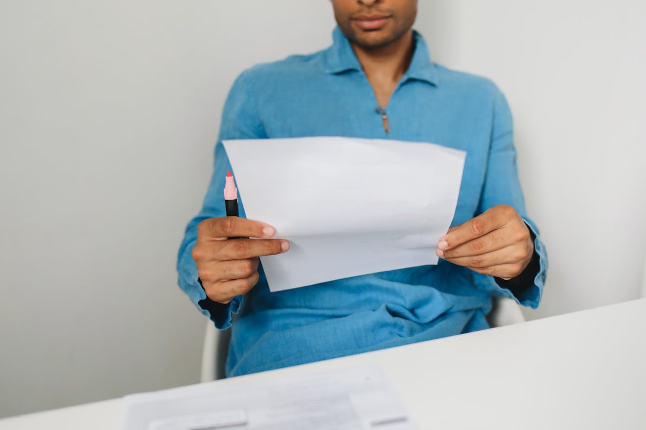 services-04 Close-up of a man holding and examining a paper with a pen indoors.